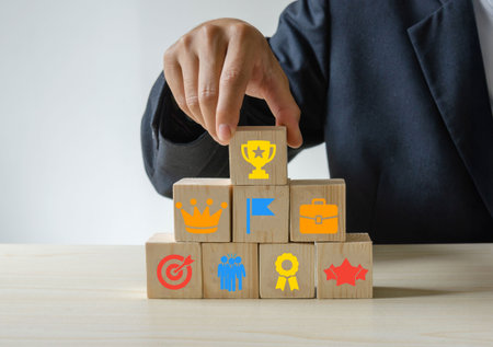 A close-up of a business leader in a professional suit stacking wooden cubes, each marked with...