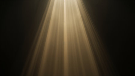 A dramatic golden beam of light streams downward into a dark space, creating a moody, cinematic atmosphere. This image conveys focus and illumination, making it suitable for advertising, branding, or editorial concepts.の素材