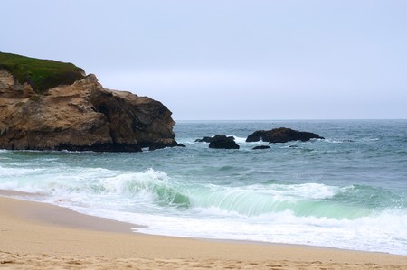 Waves crashing ashore on a foggy and cloudy California beach.の写真素材