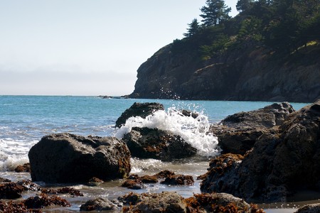 The waves crashing in on the rocks at the beach.