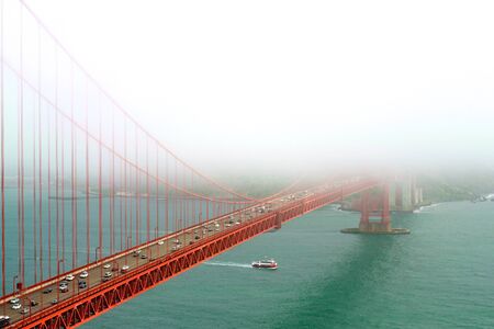 A ferry going under the Golden Gate Bridge on an unusually foggy day.の写真素材