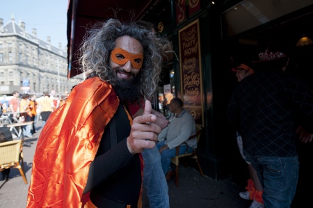 Bearded man with crazy gray hair in bright orange fancy dress celebrating Dutch national holiday Queen's Day in April 2011 in Dam Squareのeditorial素材