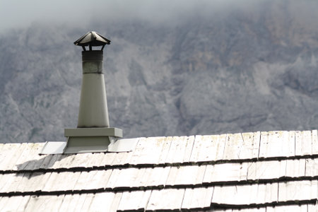 Roof and chimney of an old house with a view of the mountainsの写真素材