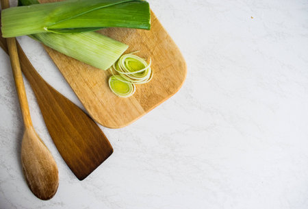 Cooking healthy food. Sliced and chopped leek on wooden cutting board isolated at white backgroundの写真素材