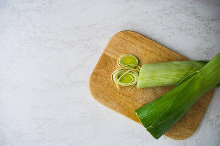 Cooking healthy food. Sliced and chopped leek on wooden cutting board isolated at white backgroundの写真素材