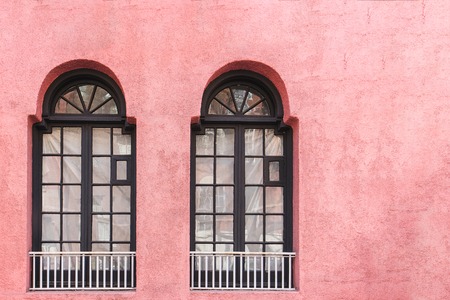 Two windows with iron bars on a pink wall. copy space for ads and textの写真素材