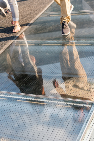 Reflection of undefined walking people on glass flooringの写真素材