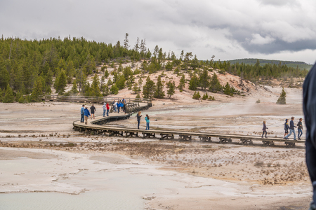 YELLOWSTONE NATIONAL PARK, WYOMING, USA - JUNE 19, 2018: Tourists at Yellowstone National Park. The boardwalk among pools and geysers. The barren snow-colored basin. Porcelain Basin of Norris Geyser Basin, Yellowstone National Parkのeditorial素材
