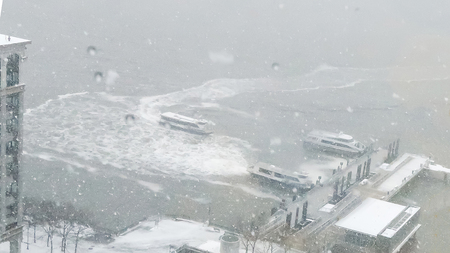 Snowfall in harbor of New York. Wind blowing fast. Stormy weather. Sudden snowstorm