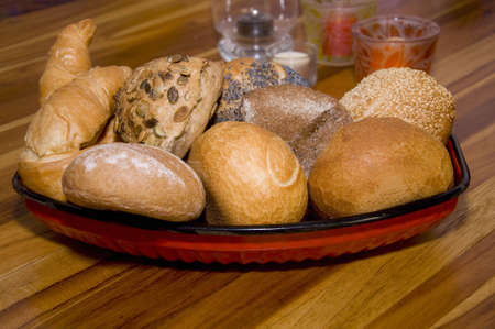 rolls and croissants on wooden table with candles in backgroundの写真素材