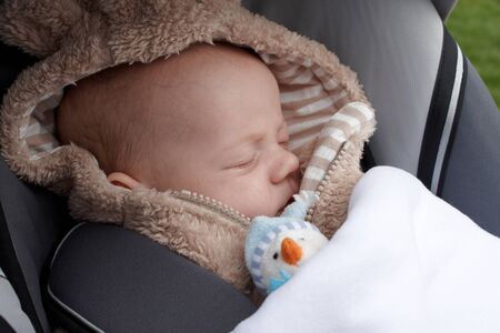 A baby asleep in a buggy with a little toyの写真素材