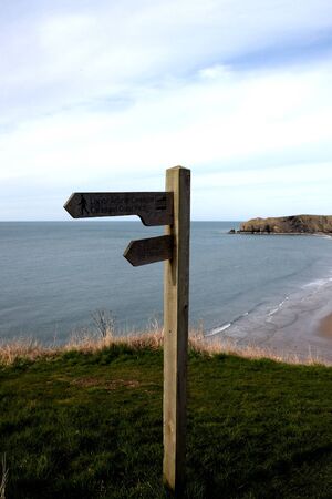 Coastal path sign post with beach in the backgroundの写真素材