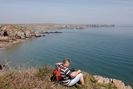 Photographer sitting on the Pembrokeshire coastal pathの写真素材