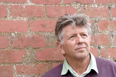 Mature man portrait with red brick wall backgroundの写真素材