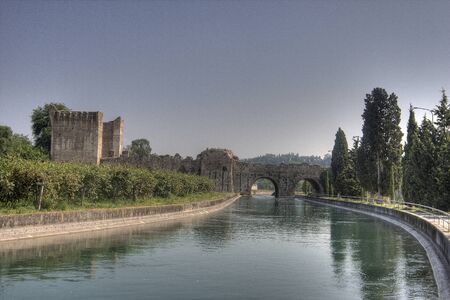 A river with a small bridge and a castle ruinの写真素材