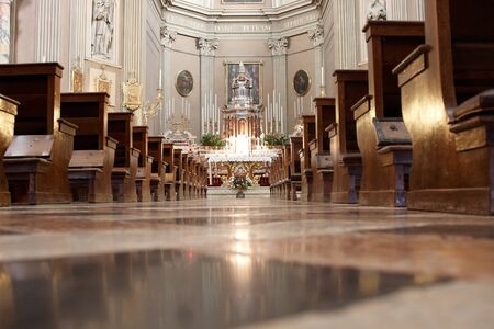 The aisle of a grand church leading towards the altar