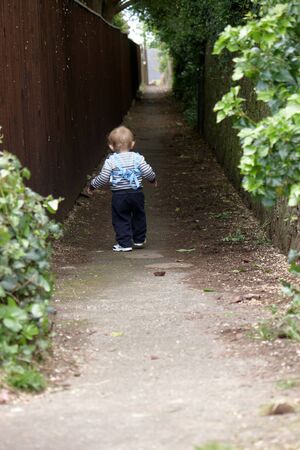 A baby boy walking down a narrow laneの写真素材