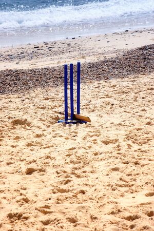 Cricket wickets  and a bat in the sand with sea in the back groundの写真素材