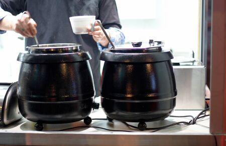 Anonymous person serving soup into a cupの写真素材