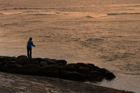 A man fishing in the sea  at sunsetの写真素材