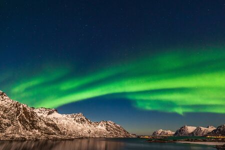 northern lights, Aurora borealis over fjord mountains with many stars on the sky in Lofoten islands,...