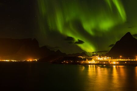 polar lights aurora borealis, northern lights with many clouds and stars in the sky over village and...
