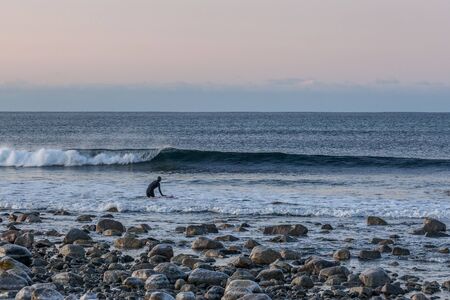 Surfing on picturesque arctic beach on Lofoten islands in Norway, the iconic travel destination for surfers of all over the world.の写真素材