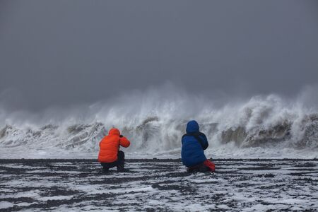 Photographers photographing the ocean during a storm in Iceland. strong wind. long exposure