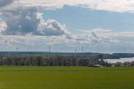 Stormy sky over a green sown field. Beautiful spring landscape with wind power on the background....