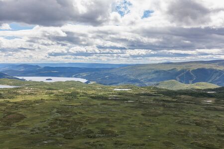 Green grass fields in Norway countryside near mountains. Cloudy foggy summer day, norwegian rural...