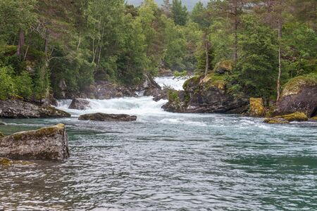 Nature of Norway. Mountain river with clear water. Rocky slope with a picturesque waterfall. Hiking...