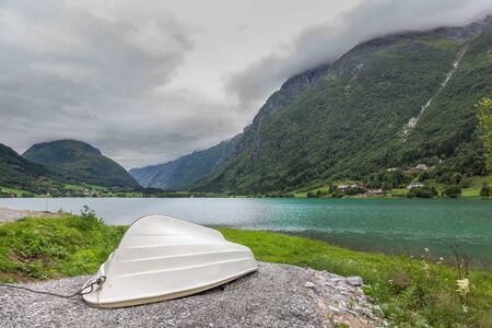 Fishing boat on a still lake in Norway and high mountains in background. Norwegian landscape with a...