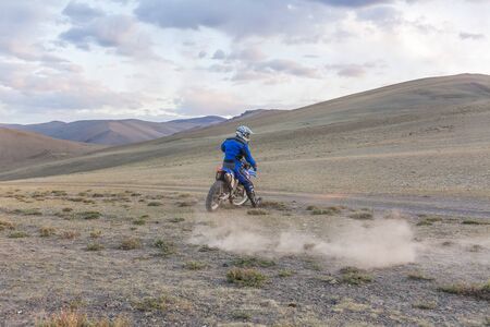 Man riding a motor cross bike in the steppes of Mongolia, on the hills of Mongolia.の写真素材