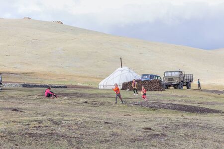 Altai, Mongolia - June 14, 2017: children run after cars with tourists and greets them.