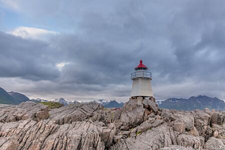 White lighthouse in Norway. Norwegian scenic landscape with a tall white lighthouse. Lighthouse on the background of harsh Scandinavian nature. Norway.の写真素材