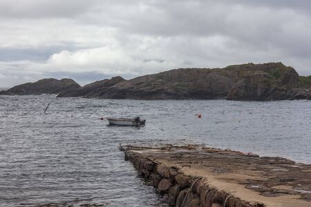Lofoten, Norway - June 20, 2017: Impressive summer view of fjord in Norway. Fishing boat in the water of the Norwegian fjords in cloudy day. Beauty of nature concept background.の写真素材