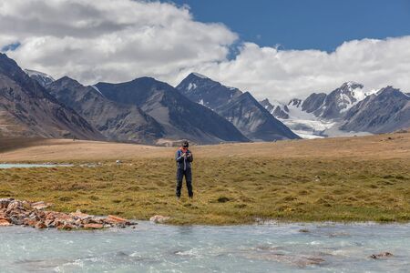 A tourist looks at a photograph of the mountains of the Mongolian Altai on its mobile phoneの写真素材