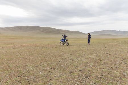 Altai, Mongolia - June 14, 2017: Father takes pictures of the happy son. Boy sitting in a helmet on a motorcycle in Mongolian Altaiの写真素材