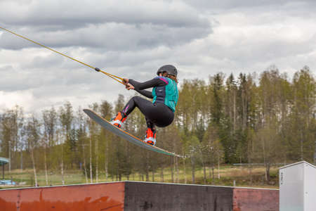 Fagersta, Sweden - Maj 07, 2020: Teen girl make an extreme jump on wakeboarding, around there are a lot of splashes, Upside down on a wakeboard.のeditorial素材