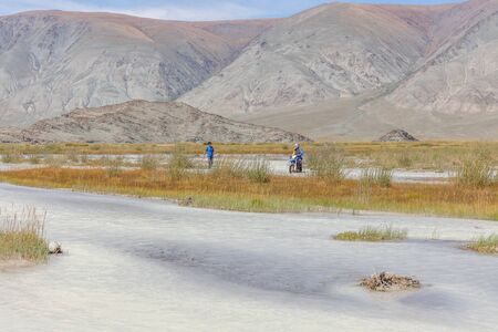 a motorcyclist is waiting for his friend to help transport motorbikes across a mountain river, Mongolia, Altaiの写真素材