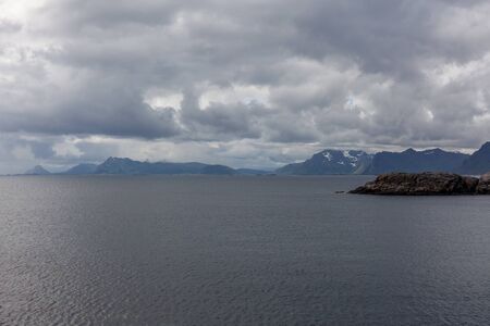 Norwegian fjord and mountains surrounded by clouds, midnight sun, polar day, ideal fjord reflection in clear water. selective focus.の写真素材