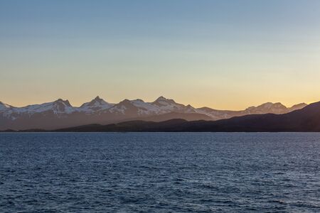 Norwegian fjord and mountains surrounded by clouds, midnight sun, polar day, ideal fjord reflection in clear water. selective focus.の写真素材