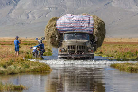 Altai, Mongolia - June 14, 2017: Tourists take pictures of the truck carrying hay on a road covered with water after a floodのeditorial素材