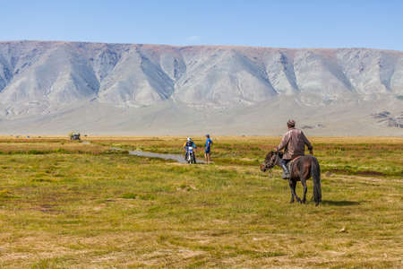 Altai, Mongolia - June 14, 2017: Mongolian nomad looks at tourists whose motorcycle is broken.のeditorial素材