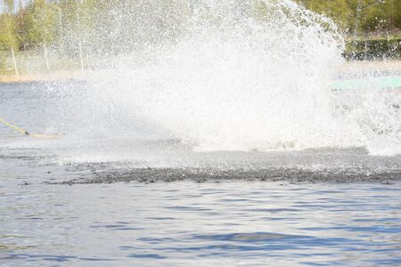Teen Wakeboarder on wakeboard landed in water surrounded by spray. Wakeboarding is an extreme sport.の写真素材