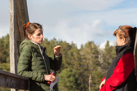 Two women are talking to each other while on a wooden bridgeの写真素材