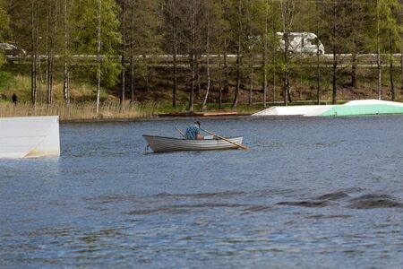 A man on a boat on te lake looks at his phoneの写真素材