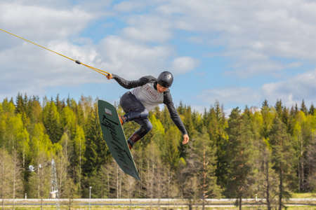 Fagersta, Sweden - Maj 26, 2020: Wakeboarding. Teen Wakeboarder makes extreme Jump in air on wakeboard. Guy flies in the skyのeditorial素材