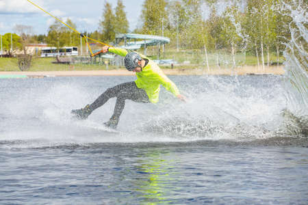 Fagersta, Sweden - Maj 26, 2020: Teen Wakeboarder on wakeboard landed in water surrounded by spray. Wakeboarding is an extreme sport.のeditorial素材