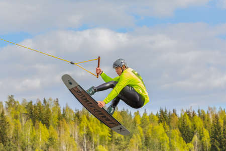 Fagersta, Sweden - Maj 26, 2020: Wakeboarding. Teen Wakeboarder makes extremely difficult jump in air on wakeboard. Guy flies in the skyのeditorial素材